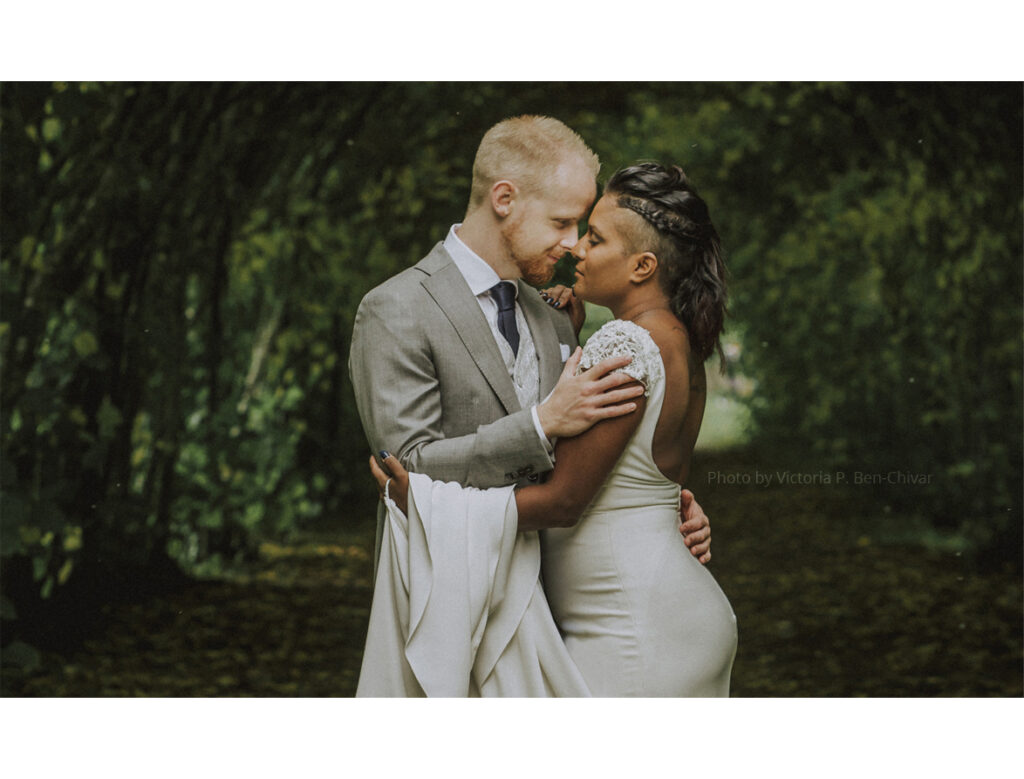 Wedding_Photoshoot_2021_at_ängsö_slott_under_arch_hugging_bride_in_white_dress_groom_in_grey_suit